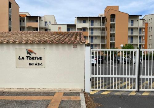 une clôture blanche avec un panneau sur le côté d'un bâtiment dans l'établissement Au bord de l'eau - Appartement cosy au Cap d'Agde, au Cap d'Agde