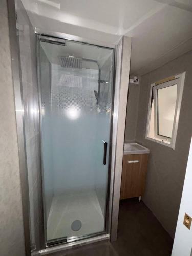 une douche avec une porte vitrée dans une salle de bain dans l'établissement Mobil-home sud ardeche 6 personnes avec clim, à Orgnac-lʼAven