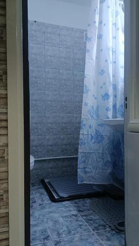 a bathroom with a shower with a blue shower curtain at Olimp SeaSun in Olimp