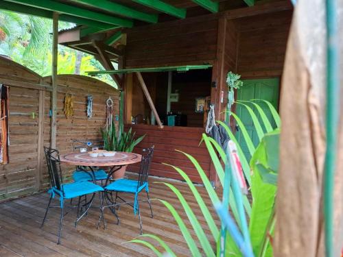 a patio with a table and chairs on a deck at Mini-Séjour pour 2 -Spa privé - Kaz créole Jade Deshaies in Deshaies
