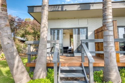 a house with a deck between two palm trees at Inverloch Motel in Inverloch
