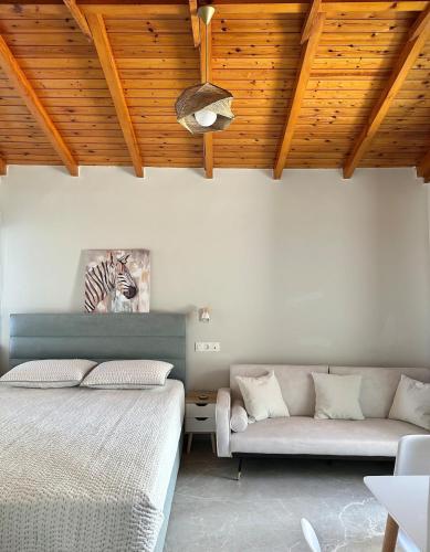 a bedroom with a bed and a couch and wooden ceilings at Mamour Apartments in Mavrovouni in Mavrovouni