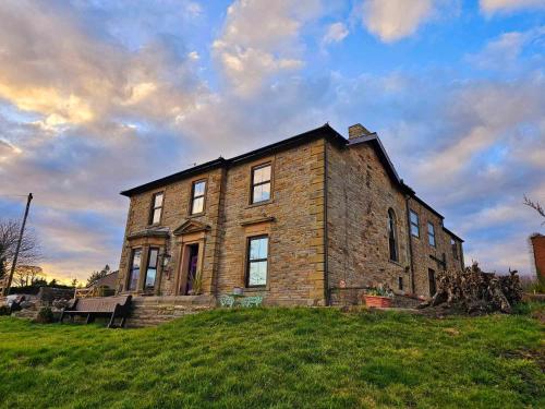 a brick house on top of a grassy hill at Greystonedale Mansion, A Grand Retreat in Northumberland in Haltwhistle