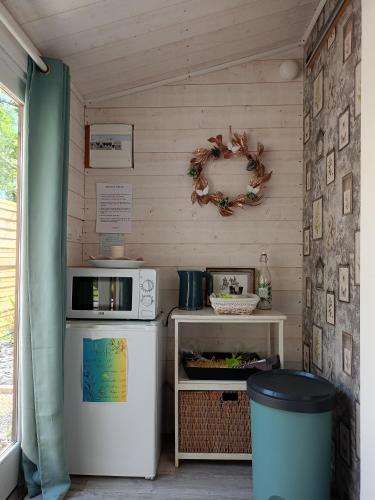 une petite cuisine avec un réfrigérateur et un micro-ondes dans l'établissement Chalet avec SPA en pleine nature 30 min des plages lac, océan et bassin d'Arcachon, à Sainte-Hélène