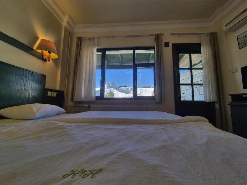 a bedroom with a large bed with a large window at Hotel HAL-TUR in Pamukkale
