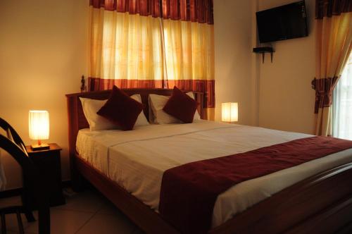 a bedroom with a bed with two lamps and a television at vino villa in Kandy