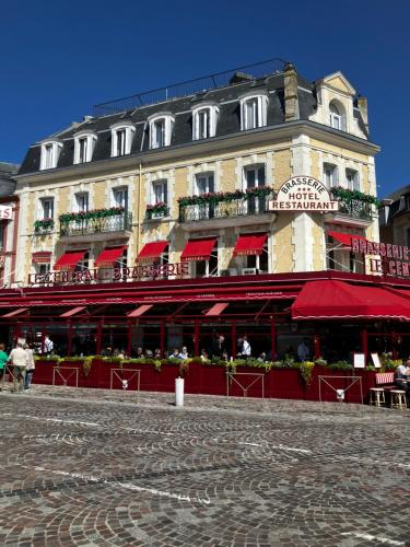 a building with red awnings in front of a building at Trouville Palace Le Bonheur in Trouville-sur-Mer