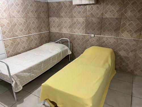 a hospital room with two beds and a yellow blanket at Casa para 9 pessoas perto da Dom Pedro 2 in Porto Alegre