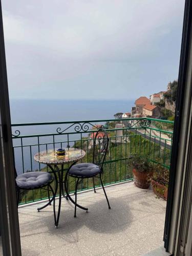 a table and chairs on a balcony with a view of the ocean at Ambra Holiday House in Furore