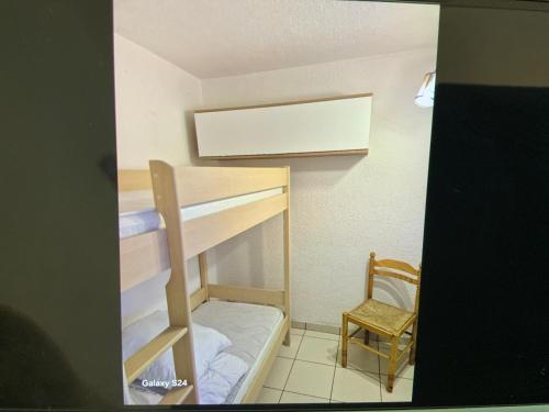 Cette petite chambre comprend des lits superposés et une chaise. dans l'établissement Apt t2/4 pers/ rez de jardin\pinède\piscine, au Cap d'Agde