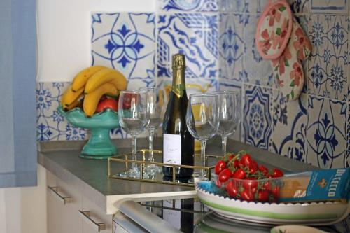 a counter with glasses and a bottle of wine and a bowl of fruit at Ambra Holiday House in Furore