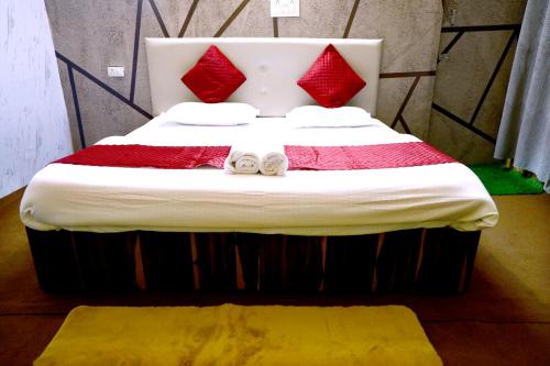 a large bed with red pillows and towels on it at The Escapee Resort in Mussoorie