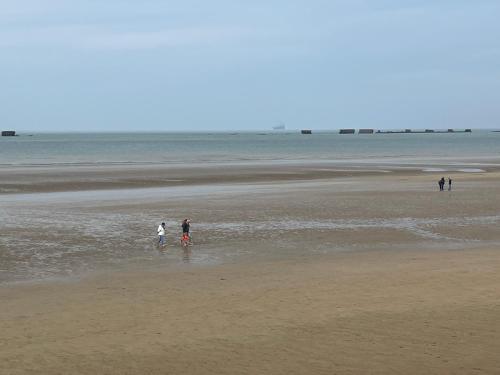 a group of people walking in the water on a beach at Chambres d’hôtes de l’Ancienne Auberge in Thaon