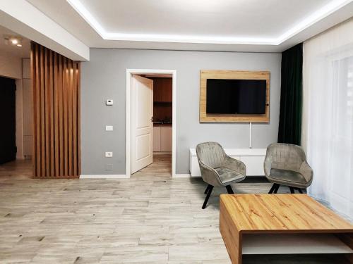 sala de estar con 2 sillas y TV en la pared en Elite Center Apartment, en Oradea