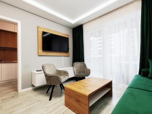 Una sala de estar con un sofá y dos sillas y un televisor. en Elite Center Apartment, en Oradea