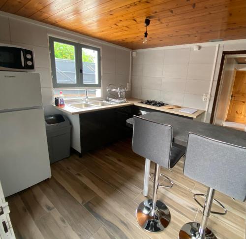a kitchen with a sink and a counter with chairs at La Madeleine in Cilaos