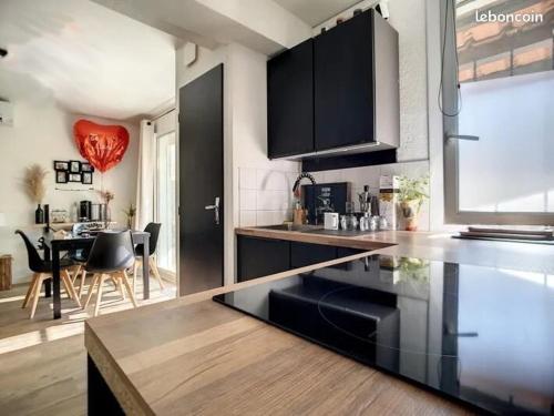 une cuisine avec des armoires noires et une salle à manger dans l'établissement Joli appartement climatisé avec extérieur, à Rognac