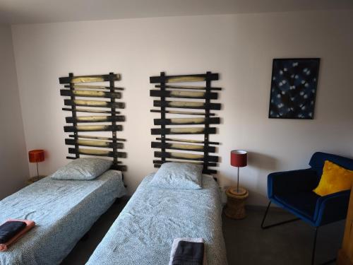 a bedroom with two beds and a blue chair at Près colmar 6 in Wolfgantzen