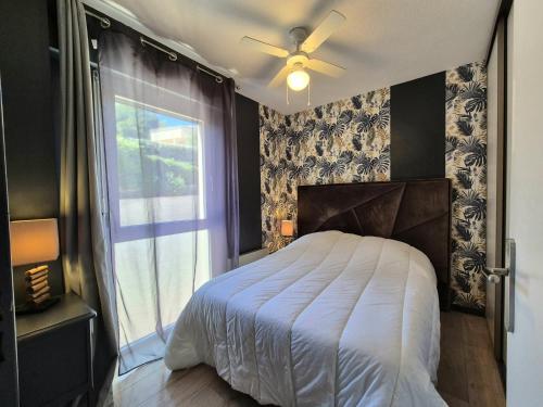 - une chambre avec un lit, un ventilateur de plafond et une fenêtre dans l'établissement T2 vue mer, proche plage & parking privée, à Bandol