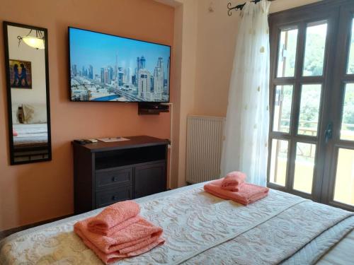 a bedroom with two towels on a bed with a television at TOBY's HOUSE in Poseidónion