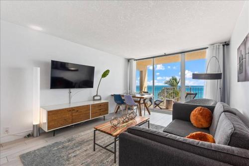 a living room with a couch and a television at Hutchinson Island BeachFront Heated Pool Balcony Top Floor Amazing View in Jensen Beach