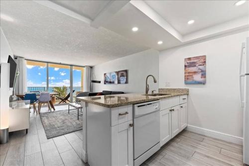 a kitchen with a sink and a living room at Hutchinson Island BeachFront Heated Pool Balcony Top Floor Amazing View in Jensen Beach