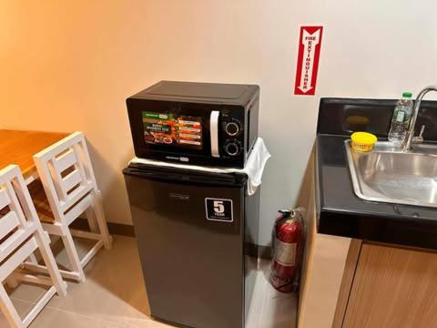 マニラにあるCharm Residences Staycation by Ashtiの電子レンジ、シンクの横の冷蔵庫