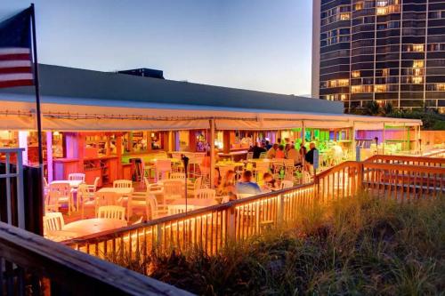 a restaurant with white tables and chairs and a building at Hutchinson Island BeachFront Heated Pool Balcony Top Floor Amazing View in Jensen Beach