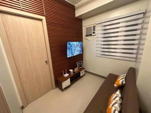マニラにあるCharm Residences Staycation by Ashtiのソファとテレビのあるリビングルーム