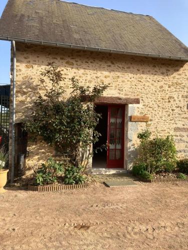 une maison en briques avec une porte rouge et une cour dans l'établissement Planchette, à Savigné-lʼÉvêque