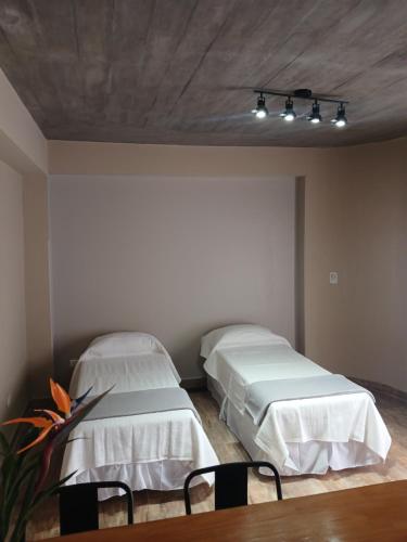 two beds in a room with two tables and chairs at Departamento Perico Jujuy in Perico