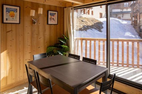 une table et des chaises dans une pièce avec une grande fenêtre dans l'établissement Val Thorens Luxury Apartment Sleeps 8, à Val Thorens