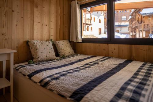 Ce lit se trouve dans une chambre en bois dotée d'une fenêtre. dans l'établissement Val Thorens Luxury Apartment Sleeps 8, à Val Thorens