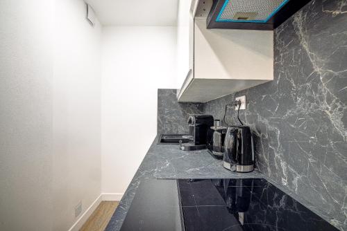 - une cuisine avec un plan de travail noir et un évier dans l'établissement Antibes proche de la plage ,Appartement lumineux et climatisé, à Antibes