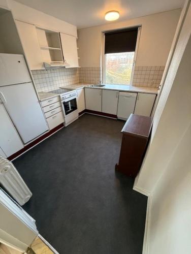 a small kitchen with white cabinets and a window at Folsted Ferie lejlighed nr 2 in Bindslev