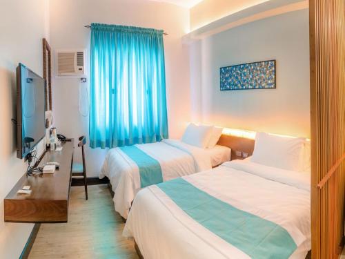 a hotel room with two beds and a television at Twin Tides Panglao in Panglao