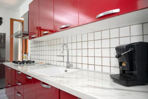 a kitchen with red cabinets and a sink with a coffee maker at The Phoenix - Modern Breathtaking Sea View Apartment with 2 Terraces, 2 Balconies, small private garden and private parking in Massa Lubrense