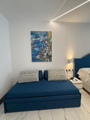 a bedroom with a blue bed and a painting on the wall at Positano Art Hotel Pasitea in Positano