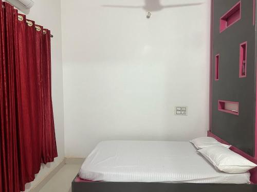 a bedroom with a bed with a red curtain at Silent River Homestay in Perdūru