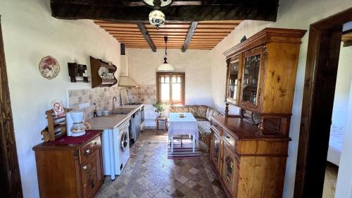 a kitchen with wooden cabinets and a table in it at Casa Maramureșeană - Refugiu Tradițional Maramureșean Cazare de Poveste în Natură lângă pârâu Loc de joaca pentru Copii Parcare Foișor in Marga