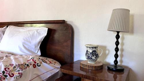 a lamp and a vase on a table next to a bed at Casa Maramureșeană - Refugiu Tradițional Maramureșean Cazare de Poveste în Natură lângă pârâu Loc de joaca pentru Copii Parcare Foișor in Marga