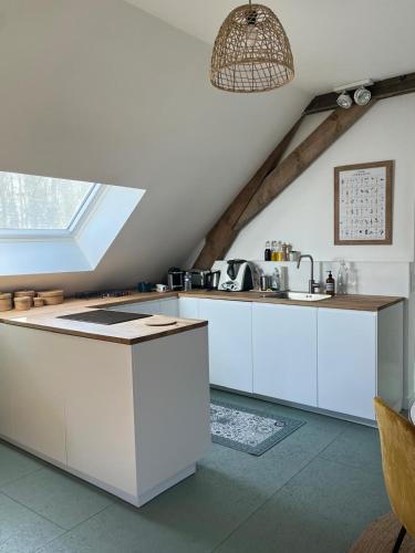 une cuisine mansardée avec des placards blancs et une fenêtre dans l'établissement Appartement T2 en pleine nature au sein d'une ferme au carré, à Wambrechies