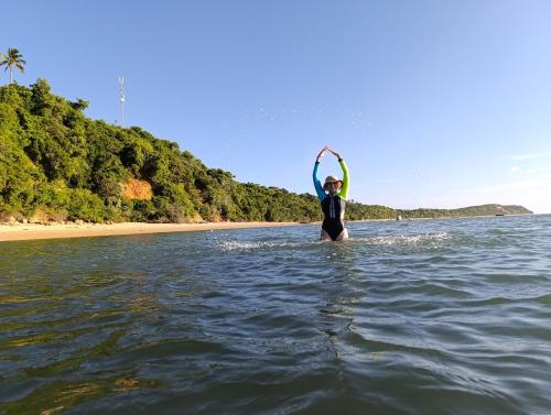 a person standing in the water with a surfboard at Machalele's House - Casa T2 acolhedora para casais e famílias na Ilha de Inhaca in Portinho da Inhaca