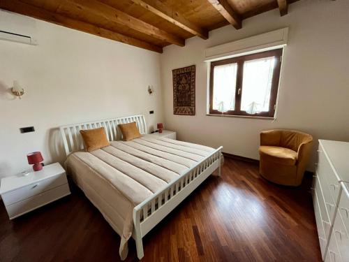 a bedroom with a large bed and a chair at Villetta Regina in Teulada