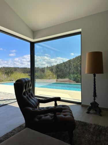 a living room with a chair and a large window at Quinta da Barrosa - Arouca in Arouca