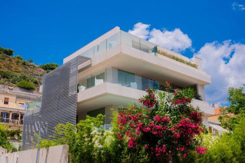 a building with pink flowers in front of it at Appartamenti Paolone House Taormina Mare in Mazzeo