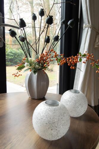 a table with a vase with a flower arrangement at Mawosy Lodge in Apeldoorn