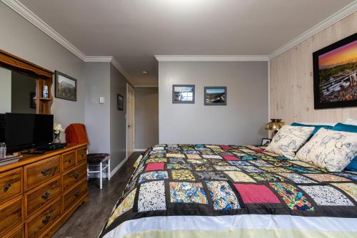 a bedroom with a bed and a dresser with a television at Out East B&B - Norris Point in Norris Point