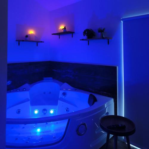 a blue room with a tub with a stool and lights at Ma douce Fenière in Saint-Rémy-de-Chargnat
