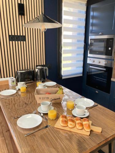 a table with plates and cups of orange juice and donuts at Grange rénovée au calme entre Rennes et Saint Malo in Vignoc